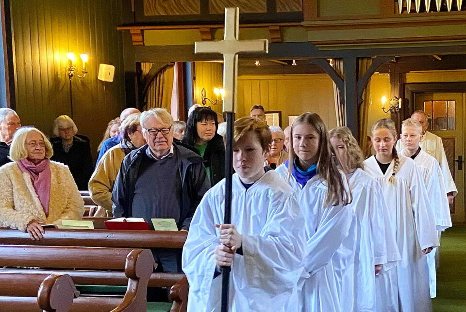 Konfirmantar og prest under prosesjon i Todalen. Korsberar er Sivert. Konfirmantar og prest under prosesjon opp midtgangen i ei kirke.