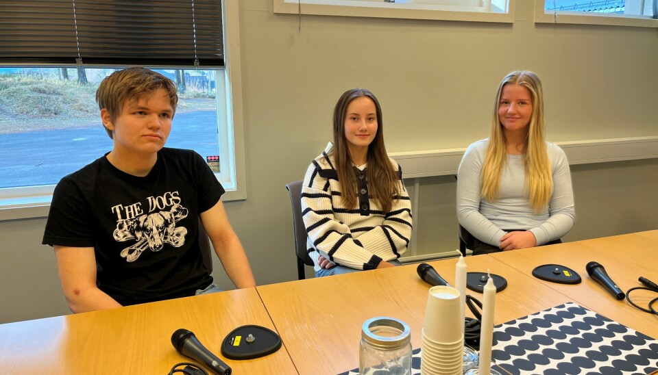 En ung gutt og to unge jenter som sitter ved et bord.