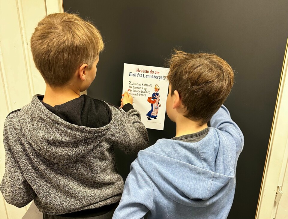 To gutter som henger opp en plakat.