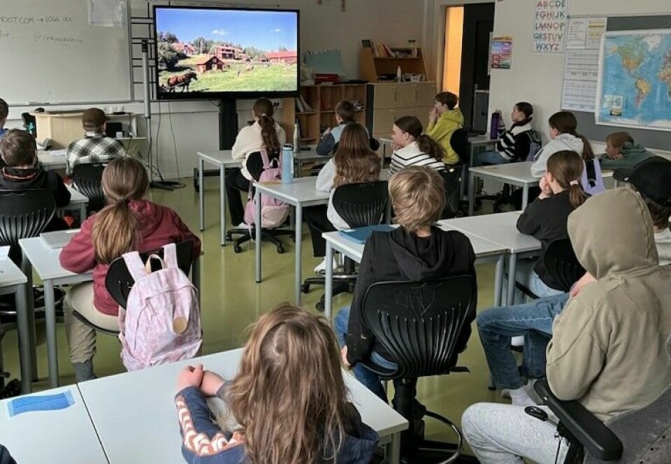 Barneskoleelever i et klasserom som ser på TV.