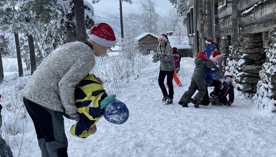 Ungdommer ukledd som nisser leker med barna i snøen.
