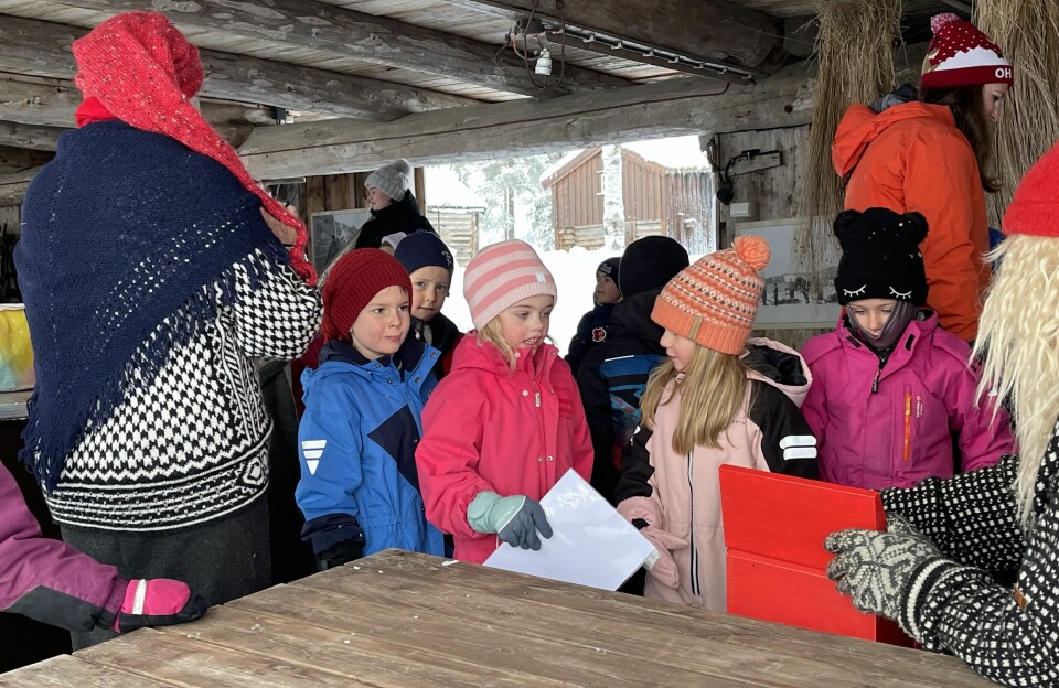 Barn i vinterklær som leverer ønskelister til nissen.