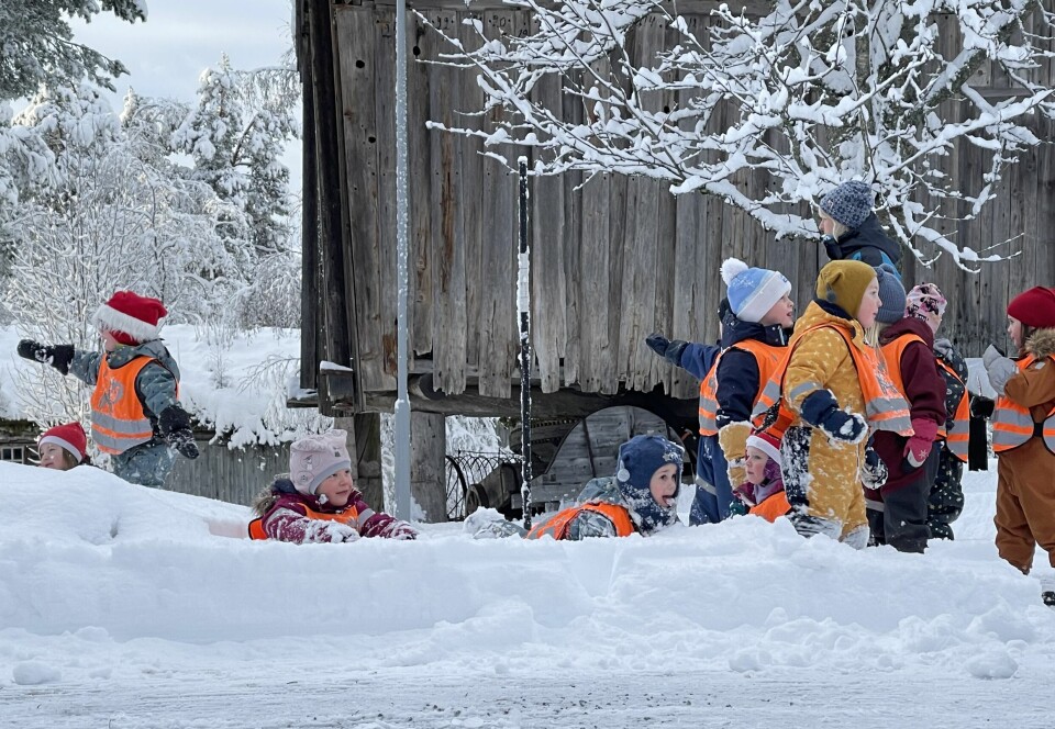 Mange barn med refleksvester som leker i snøen.