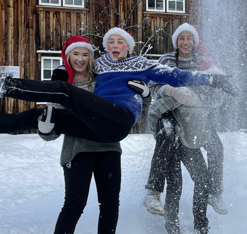 Fire ungdommer ukledd som nisser leker i snøen.
