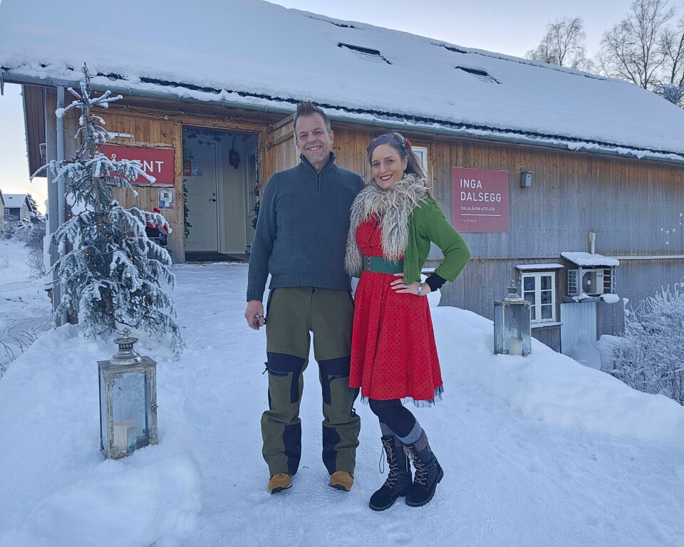 En mann og en kvinne står i snøen fpran en låve