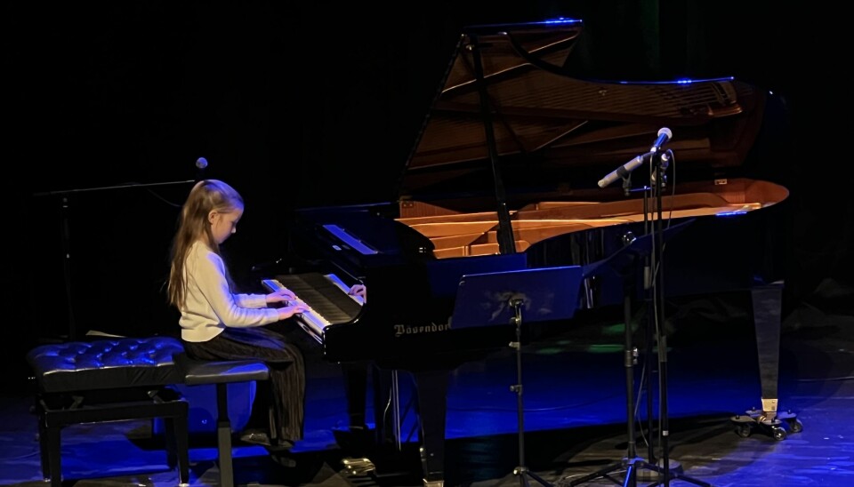 jente speler piano på scene
