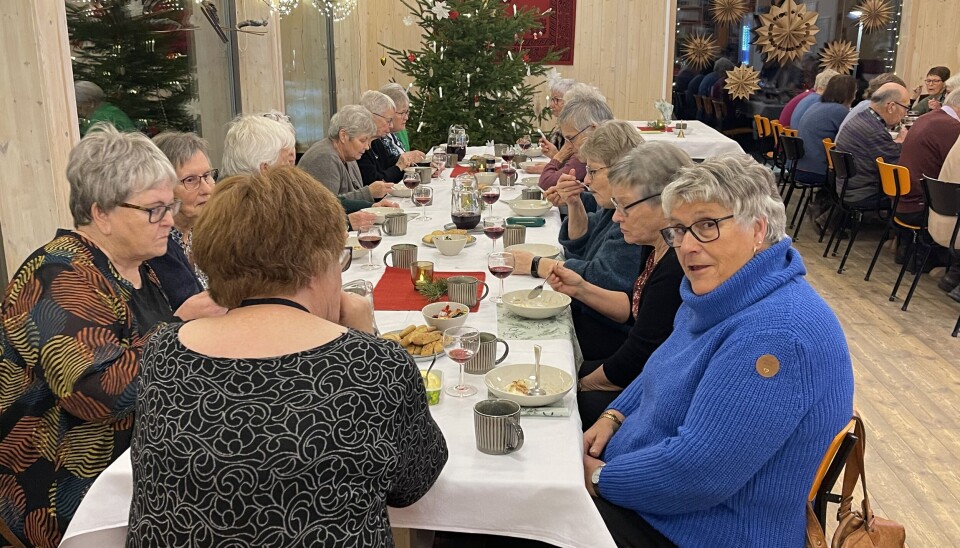 mennesker rundt et bord. Juletre i bakgrunnen.