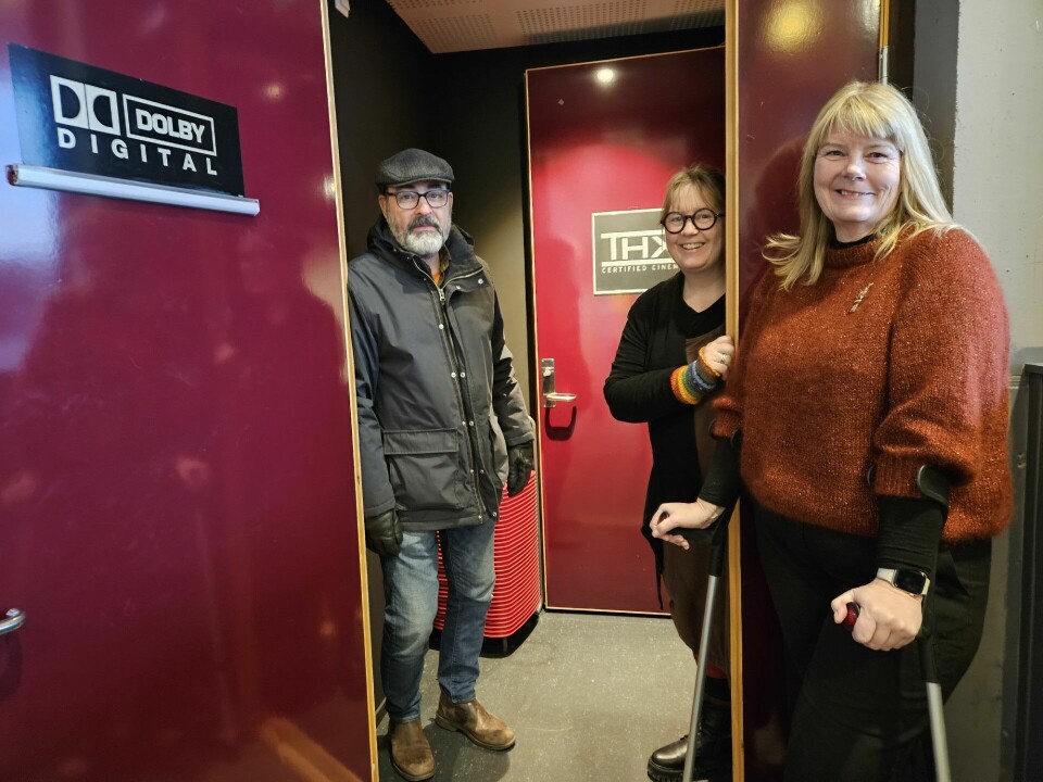 En mann og to damer står ved døren til kinoen.