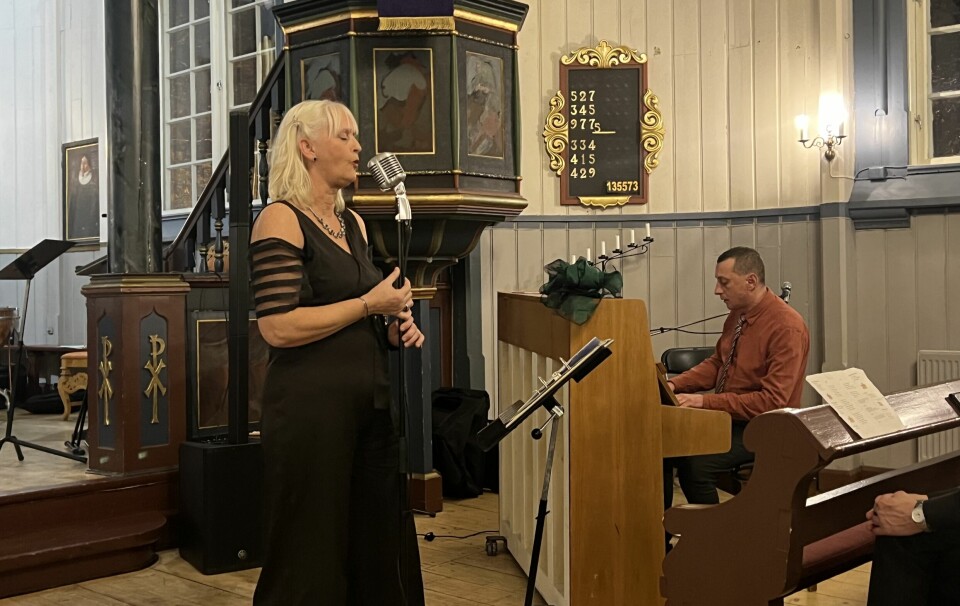 dame synger og mann spiller piano i kirke