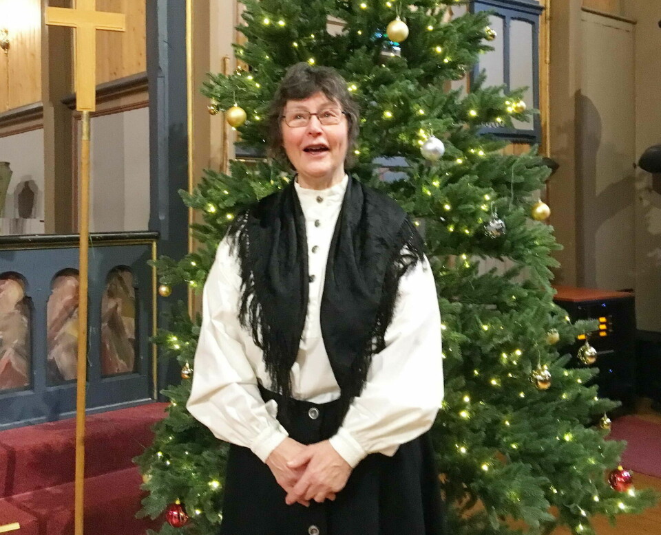En kvinne synger foran et juletre i kirka