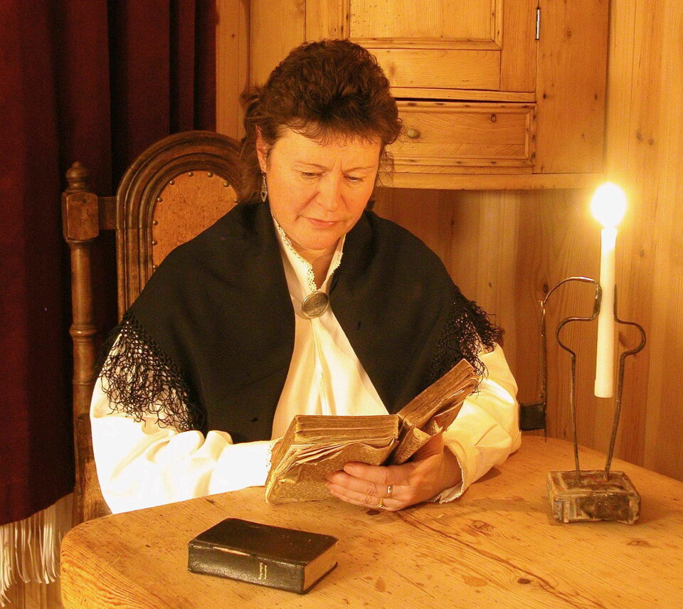 En kvinne leser en bok ved et bord med tent lys