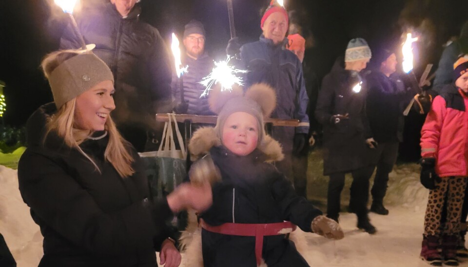 Sander og mamma vart svært nøgde med nyttårsfeiringa! mor og sønn på spark. folk med fakler i bakgrunnen