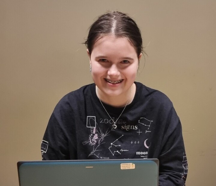 En ung jente smiler bak PC