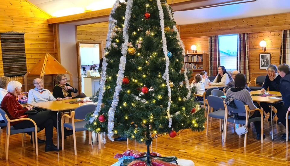 Samling rundt juletreet på Rindal Menighetshus juletre og folk ved bord