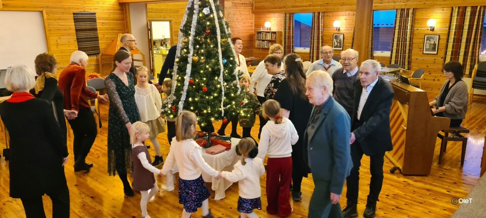 Store og små i ring kring juletreet. Folk går rundt juletreet