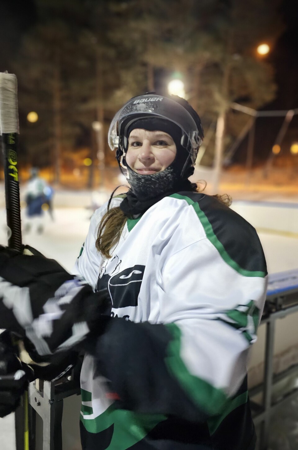 Dame i fullt hockeyutstyr venter ved vantet på sin tur på isen.