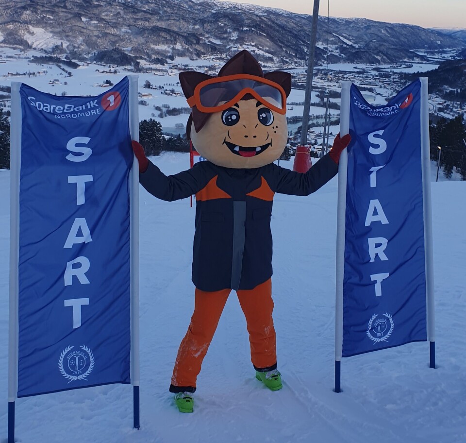 Sæterliarennet 25. - 26. januar En person utkledd som en maskot i alpinbakken, med startflagg.