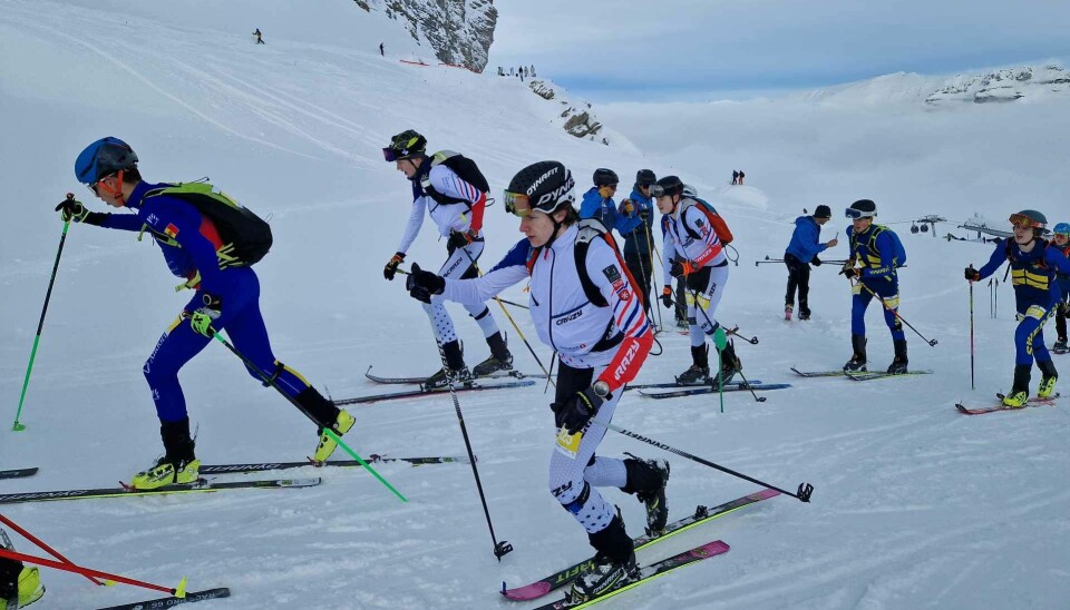 Flere skiløpere som går oppover ei fjellside.