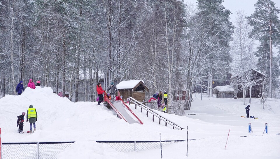 Barn leker i snøhaugen, ved sklia og i bakken ved skimuseet. Voksne følger med.