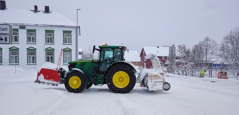 Traktor med både plog og snøfes rygger ut i Rindalsvegen for å brøte vegen bak det gamle kommunehuset på Rindal Sentrum.