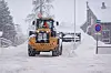 Vi ser bakenden på en gul Catepillar dumper med utslagsbar plog som skyver snøen i en allerede stor haug..