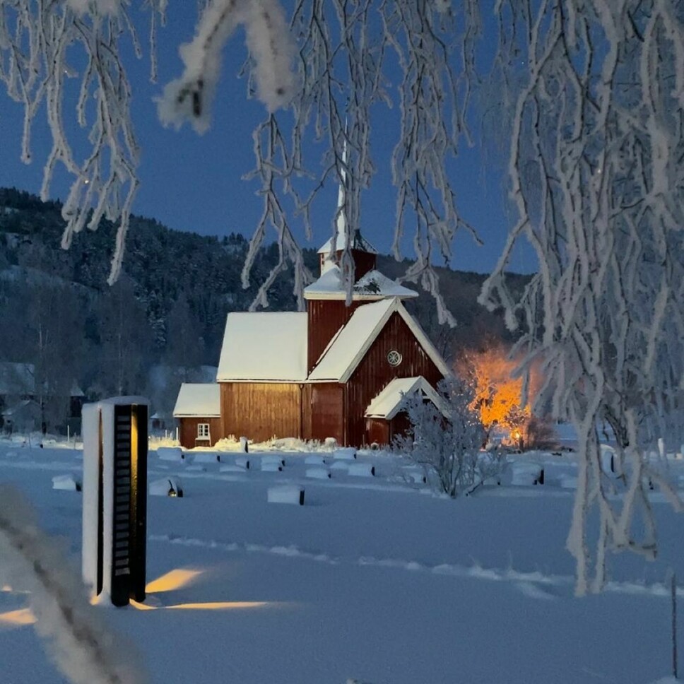 En trekirke med mye snø på kirkegården
