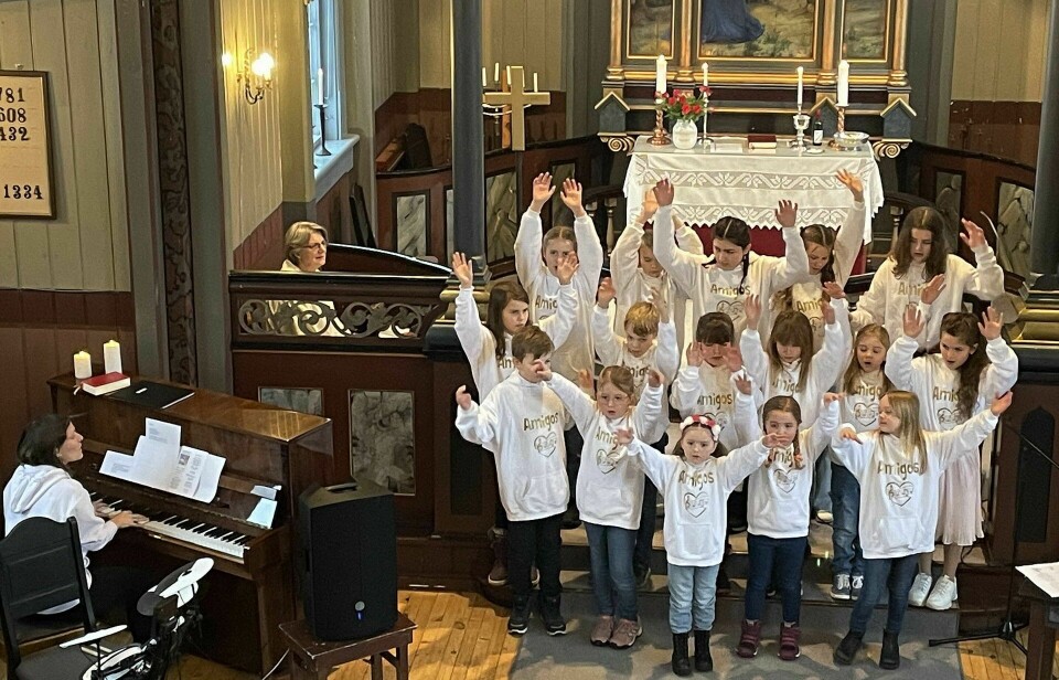 Barn i en kirke, en voksen spiller piano