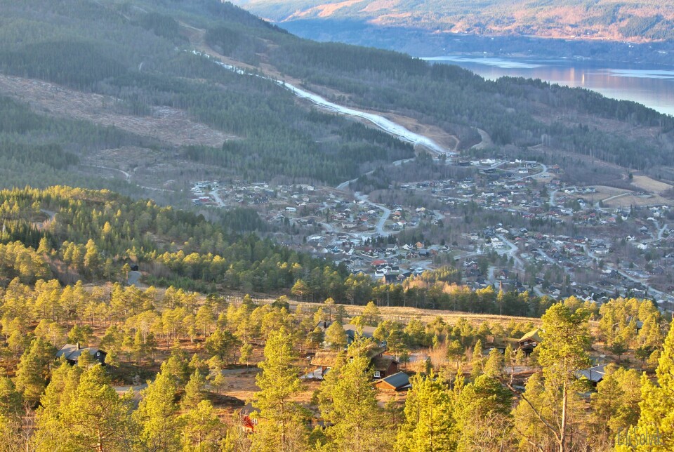 Et bilde tatt fra en høyde med et hyttefelt i forgrunnen og et boligfelt lenger nede i dalen. Utsikt til fjord og fjell.