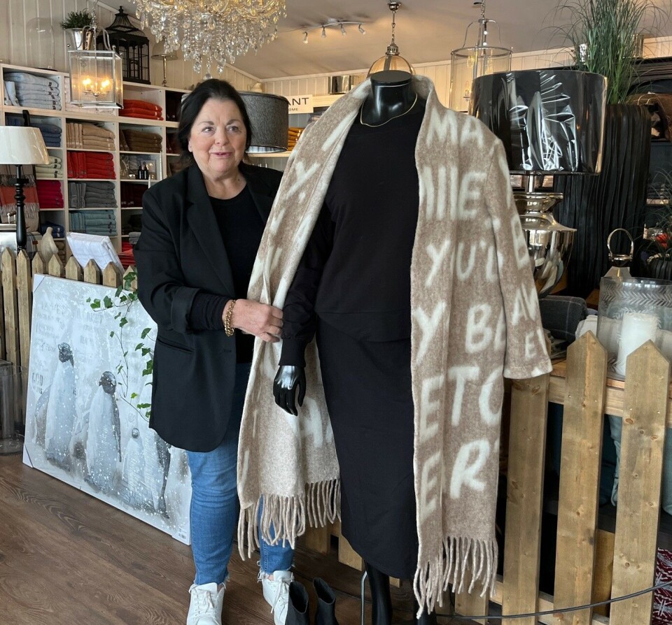 Marit Helene Aspli Harviken har drevet denne innholdsrike butikken i snart 11 år. Ei dame som stor ved siden av ei utstillingsdukke med klær.