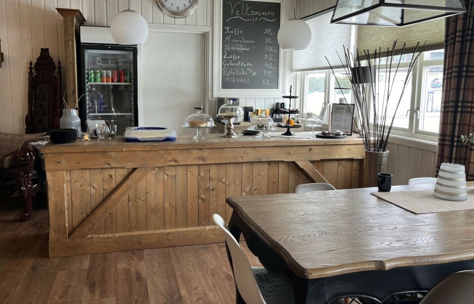 HMH Design har også en liten kaffekrok, der man får kjøpt kaffe og kaker. Em disk med kaker, og en tavle med priser på veggen bak.