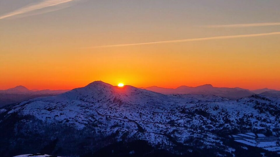 Oransje himmel og solnedgang bak fjellet