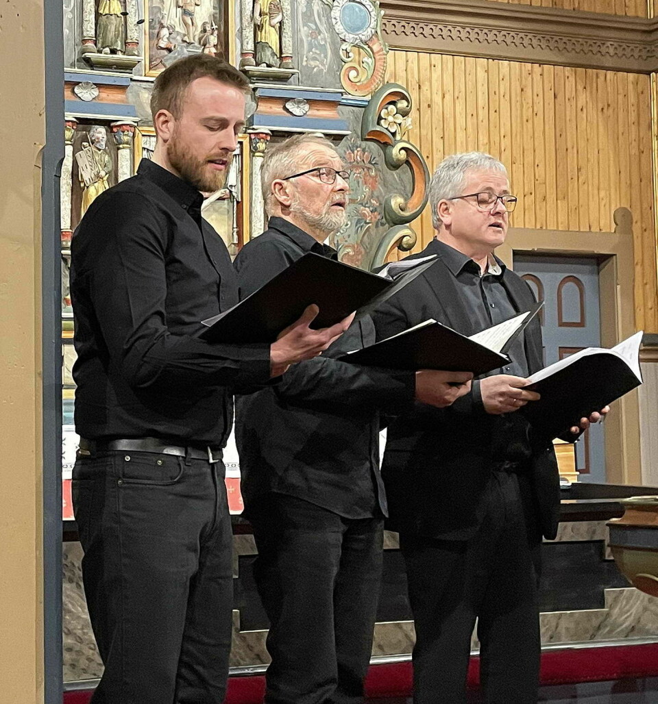 Tre menn som står og synger.