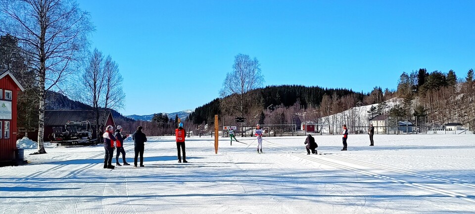 Målgang på fotballbanen på Skogsletta, oversiktsbilde som viser 8 publikummere og en fotograf ved mållinja.