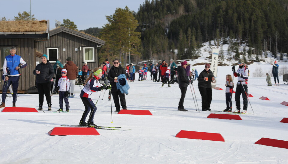 Publikum ser på at jenta på ski passerer etter første runde. Kiosken og tidtakerbua i bakgrunnen.