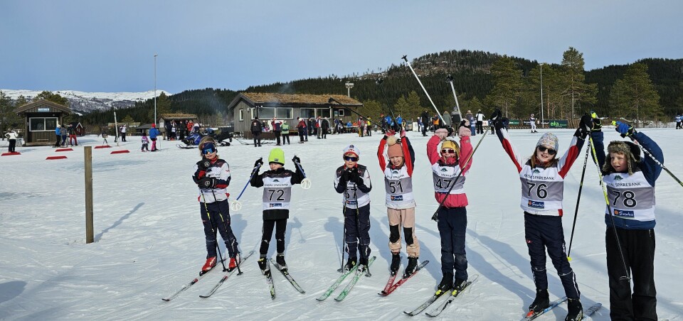 Fotografen har samlet 7 tilfeldige deltagere på rekke foran skistadion