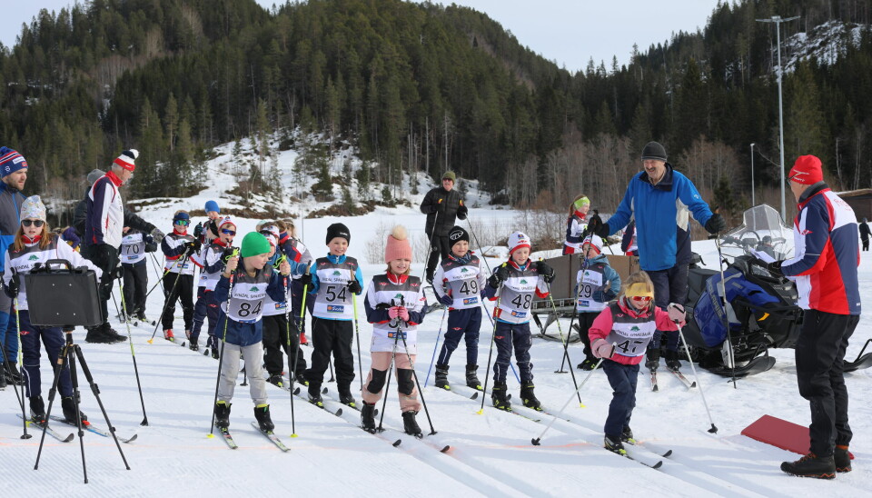 10-15 skiløpere klare til start. Til venstre står startklokka som piper når en løper skal starte.