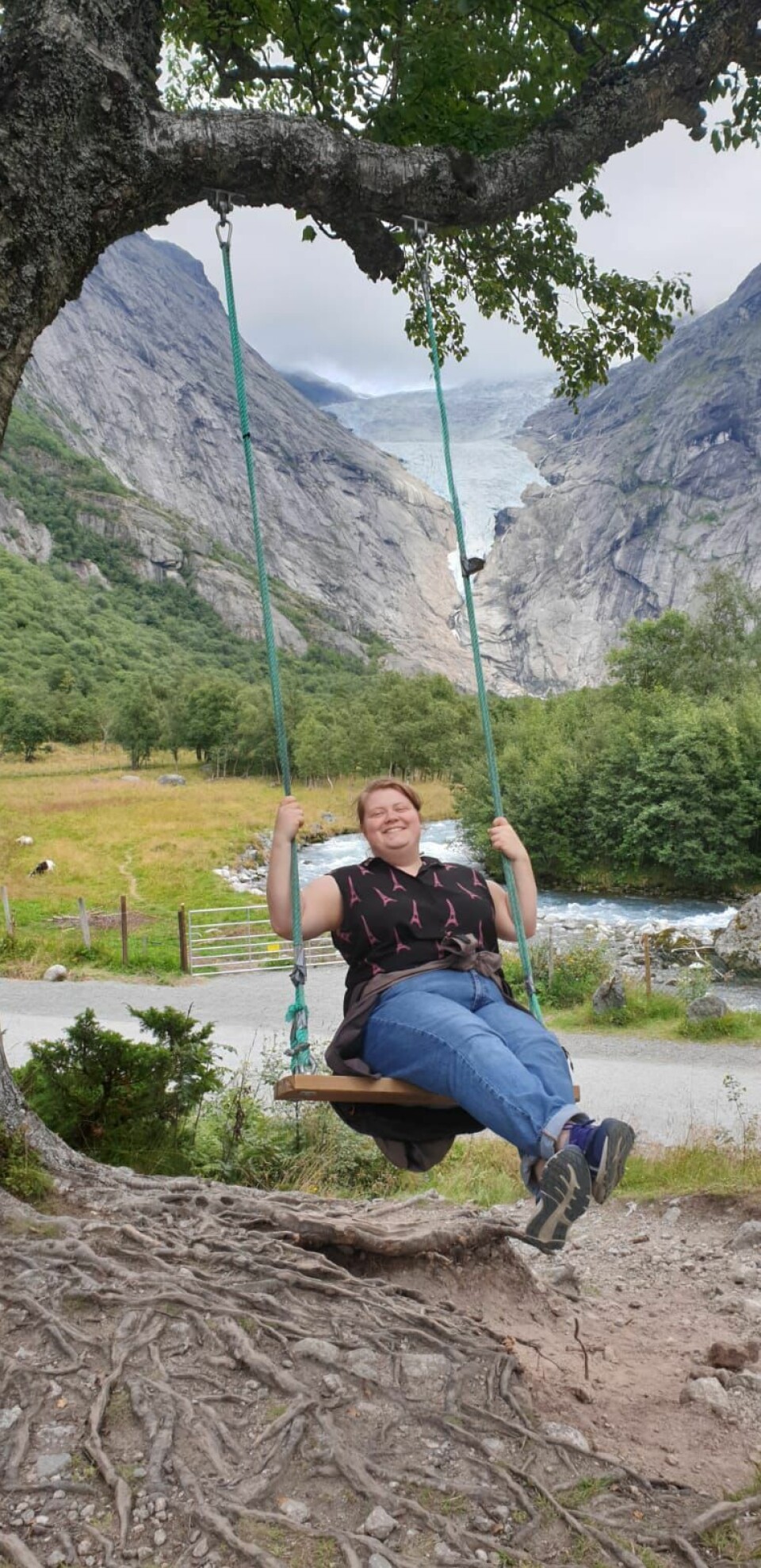 Husking med Briksdalsbreen i bakgrunnen. Dame husker på en huske som henger i et tre.