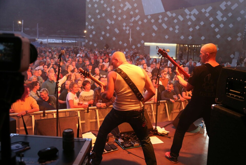 Et rockeband som spiller på en scene foran et stort publikum.