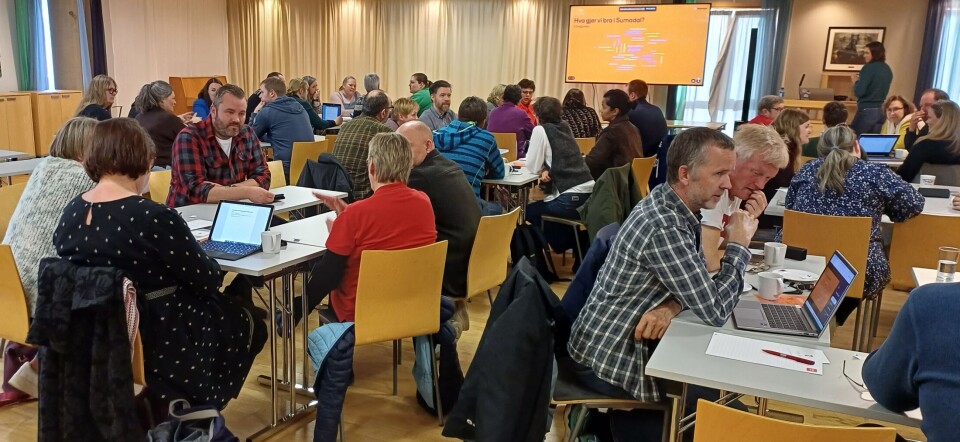 Mange engasjerte folk i diskusjon rundt bordene. Mange mennesker rundt bordene