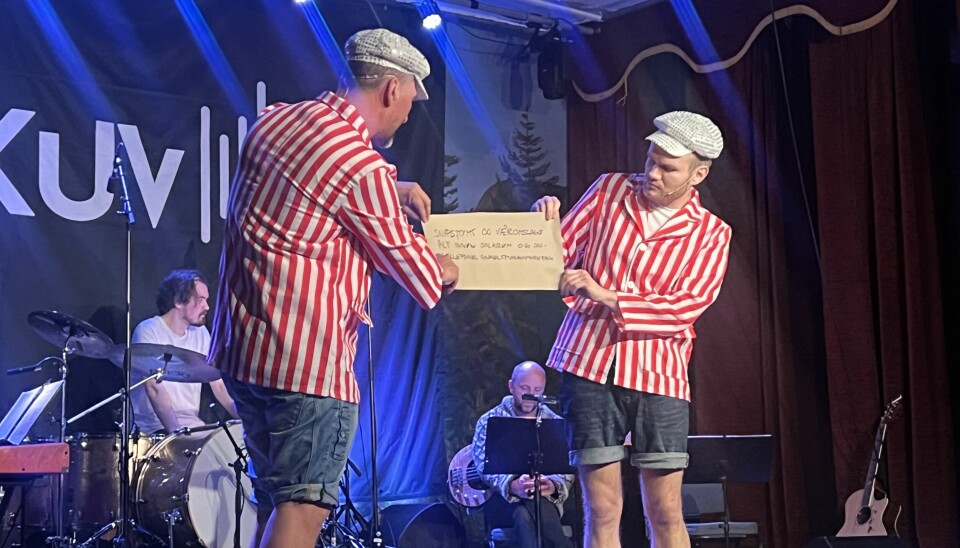 to menn i stripete skjorte holder liten plakat på scene