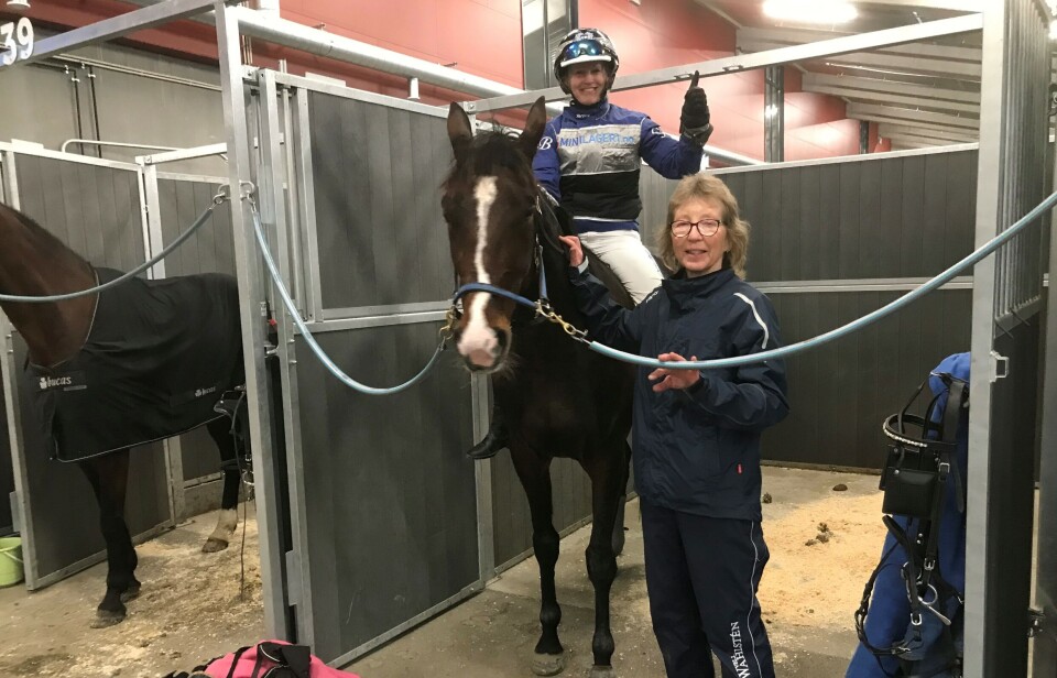 Scarselli med eier Irene Løfaldli og rytter Guro Berg. Danny Delight står ved siden av. En hest med ei konkurransekledd dame på ryggen og ei dame ved siden av. De er inne i et stallrom.