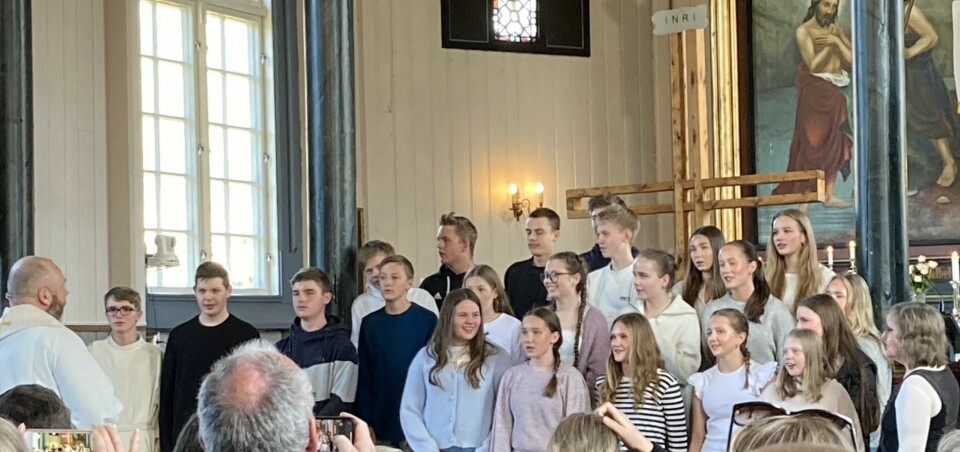 Flere ungdommer og en prest i koret i ei kirke.