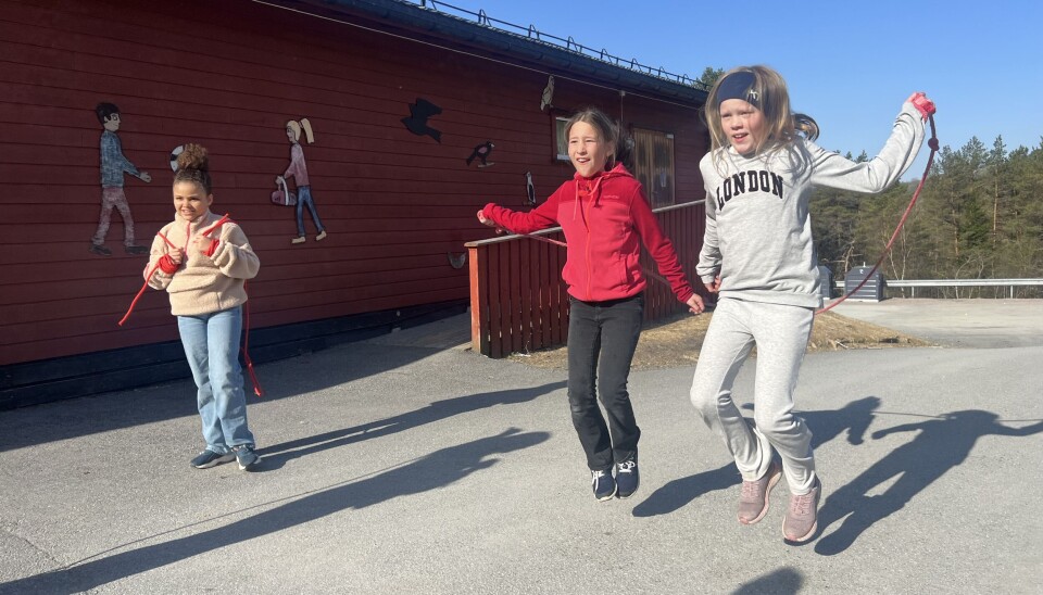 to jenter hopper hoppetau, jente står på siden med hoppetau i handa