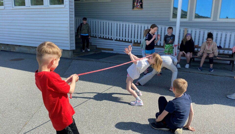 Hoppetauet kan brukes til mer enn bare hopping! Her har andreklassingene satt i gang limbo i skolegården. Jente går limbo under hoppetau, mange barn rundt