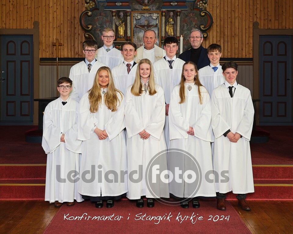 Konfirmantane i Stangvik, med prest Torbjørn Brøske og Bernt G. Bøe. Ti konfirmantar i kvite kapper, ein prest og ein mann kledd i dress, oppstilte for fotografering framme i koret i kyrkja.