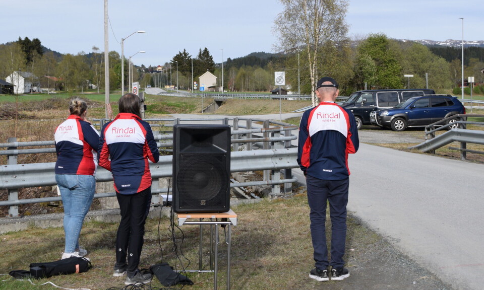 Her skimtes vinneren i det fjerne. Tre menn i idrettslagsdrakt som følger med bortover veien.