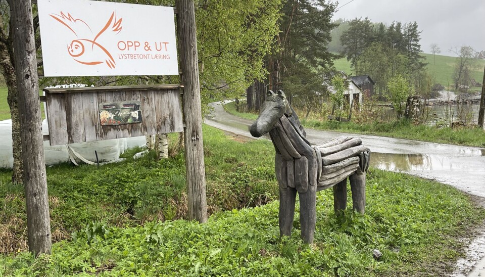 Det er lett å se når du er kommet frem til gården. Skiltet med opp og ut er på plass ved innkjørslene. Et hvitt skilt med en ugle på. Der står det Opp og ut, lystbetont læring. En hest av tre ved siden av. Regntung dag