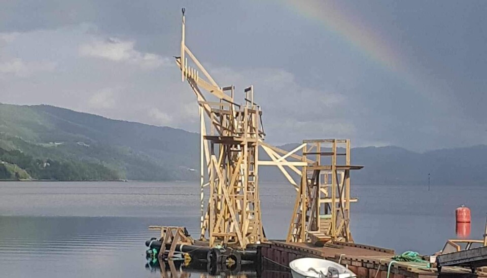 Brygga med stupetårnet på enden. En brygg med et stupetårn. bygd i tre. 7 meter høyt. Regnbuer over tårnet og fjord og fjell i bakgrunnen