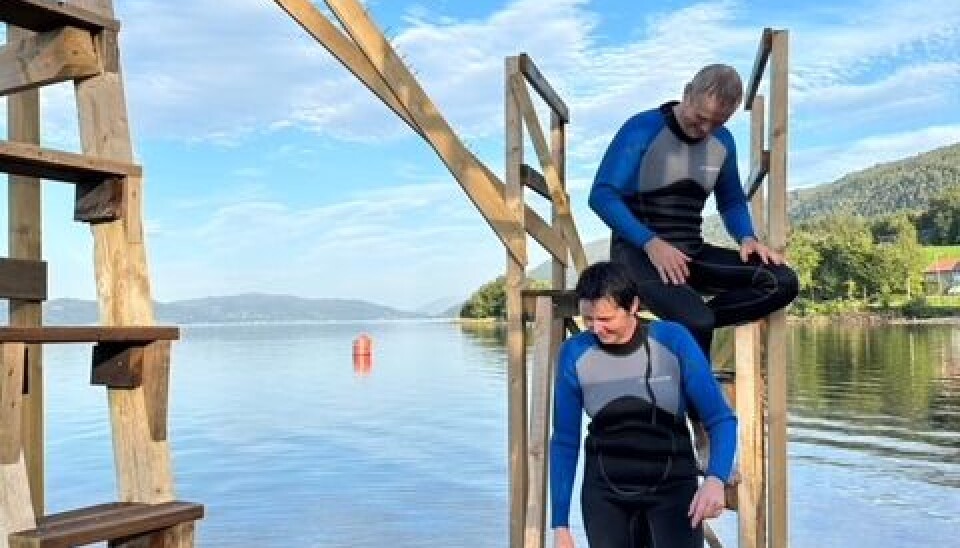 Stupertårnet er også et godt utgangspunkt for aktiviteter under vann. to personer i våtdrakt. Sitter på en trekonstruksjon. Vann i bakgrunnen. Blå himmel med noen skyer