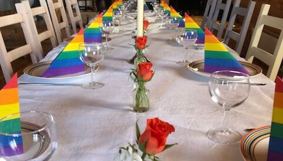 I kafèen kan de ta imot gjester for selskapeligheter i tillegg til vanlig drift. Her er bordene pyntet. Dekket langbord med vinglass, talerkener og servietter i pridefarger